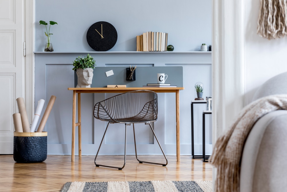 Perspective of Eco Friendly Home Office with calming blue and white colors scheme, desk placed between two doors with hardwood floors, clock, plant and objects on shelves, Interior Design