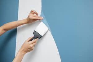 Woman's hands holds paint brush, removes wall paper, non toxic interior design