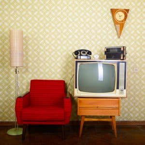 Vintage interiors with op-art wall paper, red chair, vintage TV and camera, vintage clock on wall, eclectic interior design 