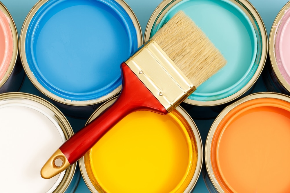 Vibrant Interior Paint hues in paint cans with paint brush resting on cans non toxic paint