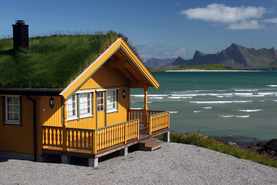 Wooden House on platform with green roof, against backdrop of seascape, beach and mountains, Green Home, Passive House, Zero Carbon Home