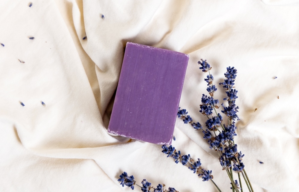Bar of lavender soap on natural bedding with lavender braanch